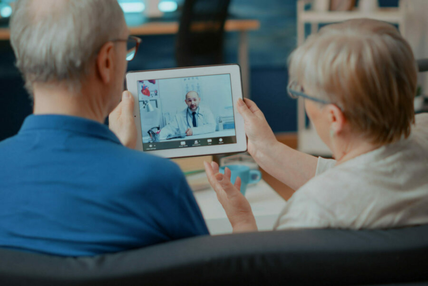 Senior couple attending online meeting with doctor on digital tablet, doing remote consultation at home. Elder people using videoconference call on modern gadget for internet telemedicine.